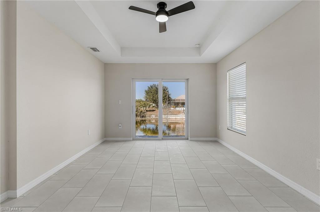 Empty room with a raised ceiling, a ceiling fan, and a water view