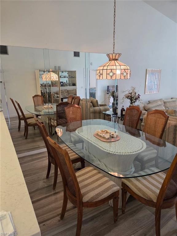 Dining area with dark wood-type flooring and vaulted ceiling
