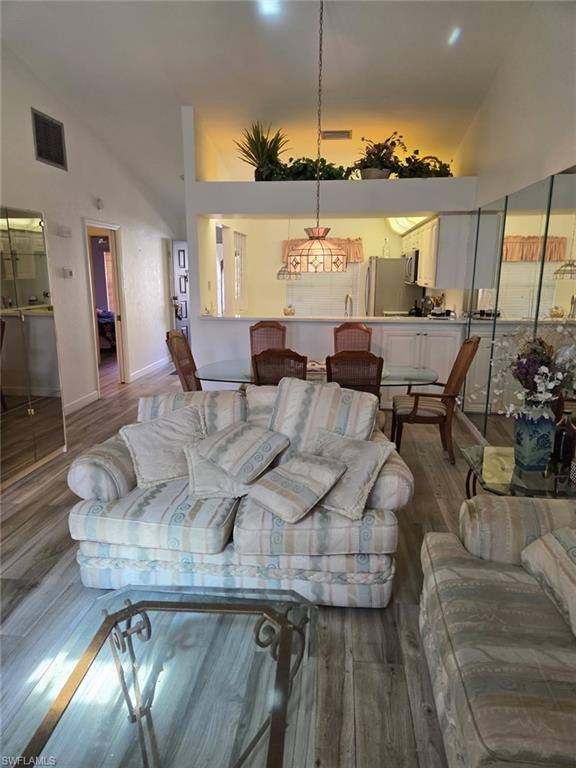 Living area featuring high vaulted ceiling and wood finished floors