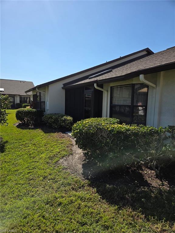 View of side of property with a lawn and stucco siding