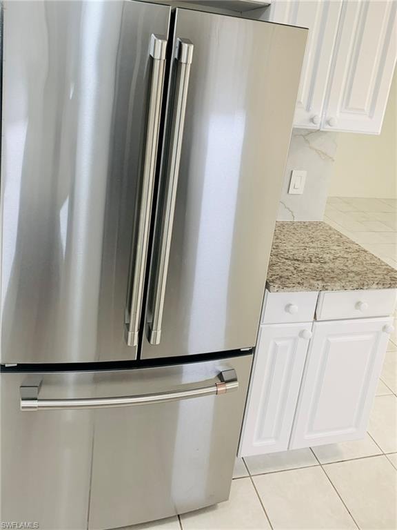 Kitchen view of high end refrigerator, white cabinets, and light stone counters