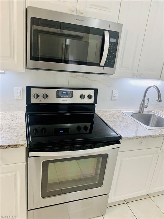 Kitchen featuring appliances with stainless steel finishes, white cabinetry, and decorative backsplash