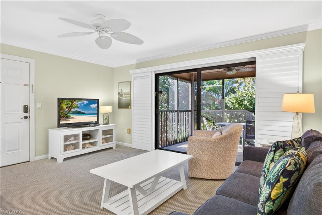 Carpeted living room with crown molding and ceiling fan