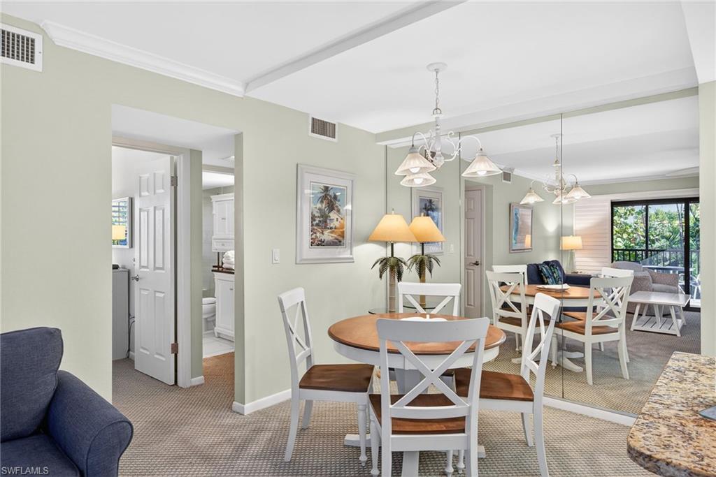Dining room featuring light carpet, crown molding, and a chandelier