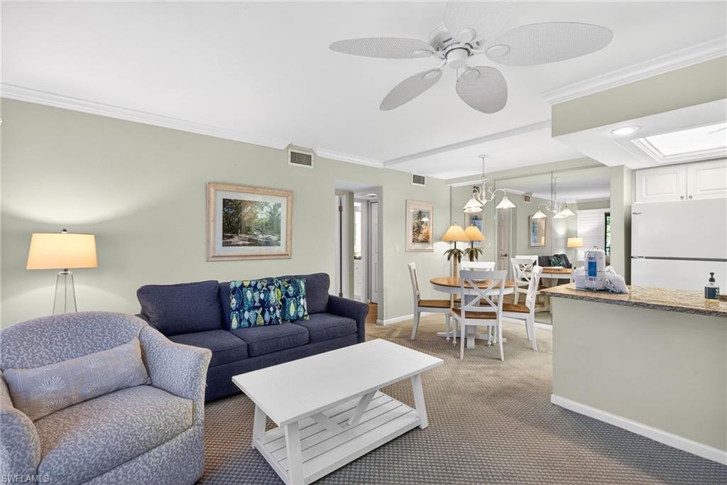 Carpeted living area featuring ornamental molding and a ceiling fan