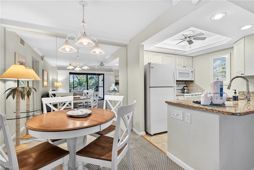 Kitchen with a ceiling fan, white appliances, white cabinetry, light stone counters, and recessed lighting