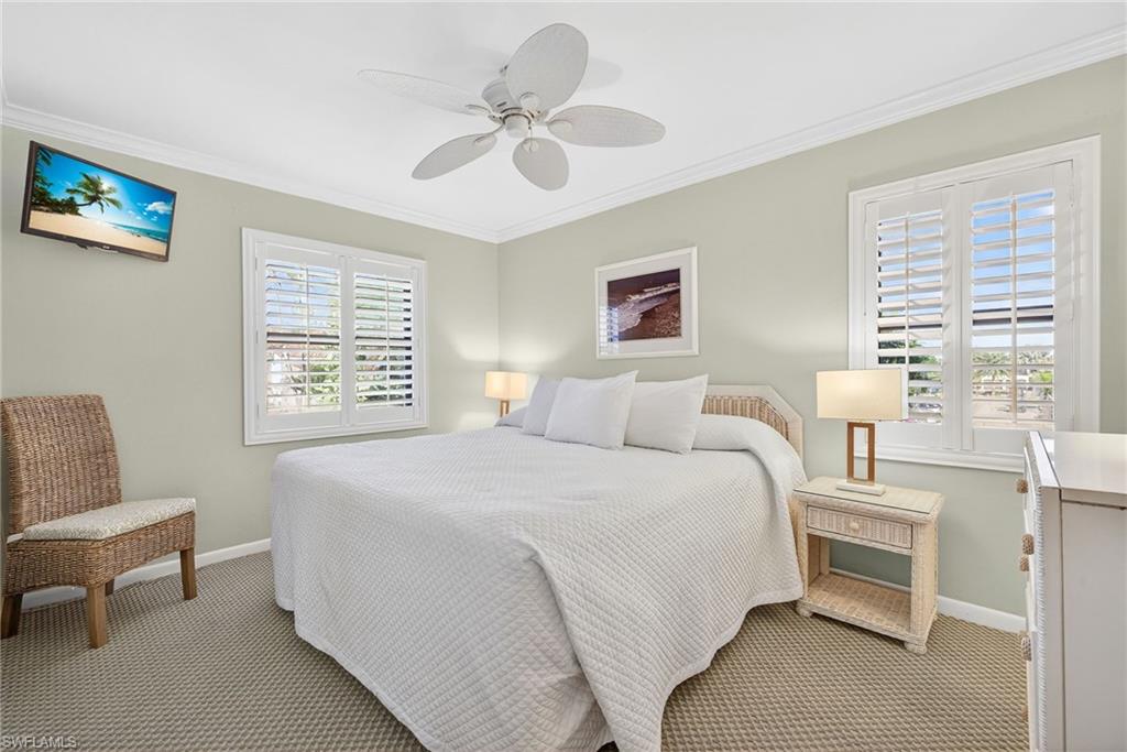 Carpeted bedroom with ornamental molding and ceiling fan