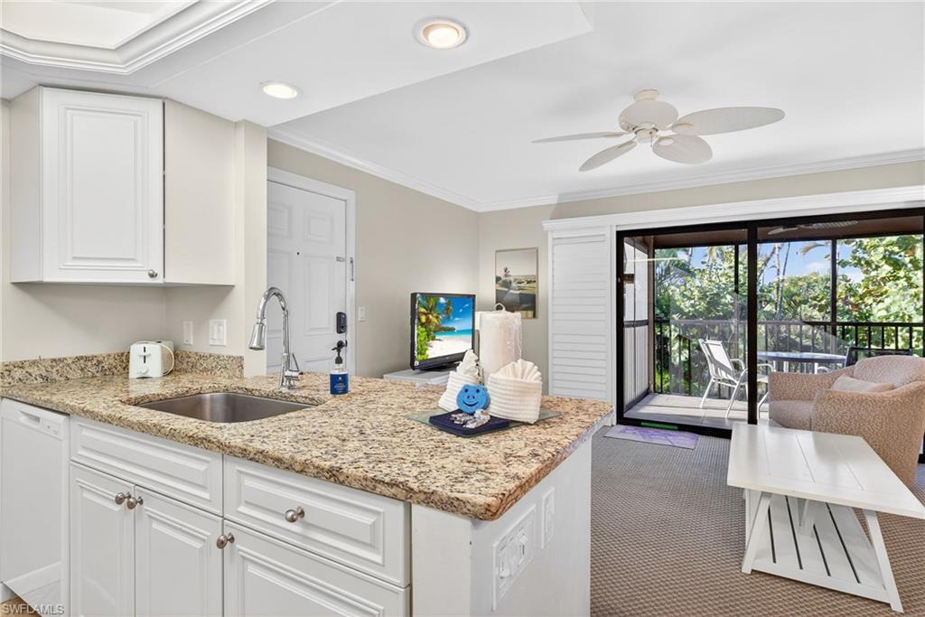 Kitchen featuring ornamental molding, light stone countertops, dishwasher, white cabinets, and a peninsula