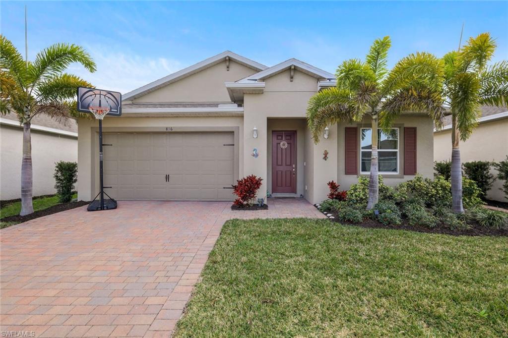 View of front of house featuring a front lawn, stucco siding, decorative driveway, and an attached garage