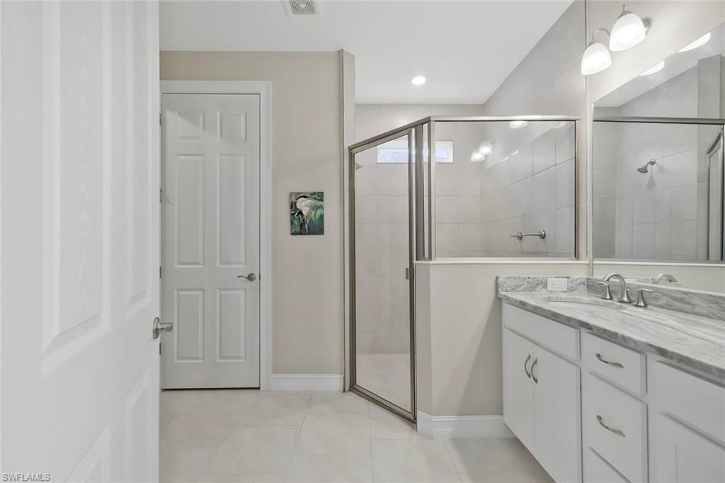 Full bath featuring a stall shower, vanity, and light tile patterned floors