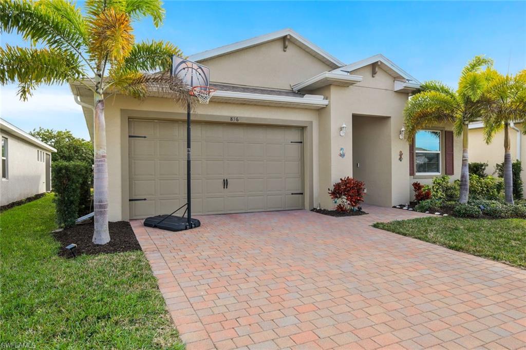 View of front of property with stucco siding, a front yard, decorative driveway, and a garage