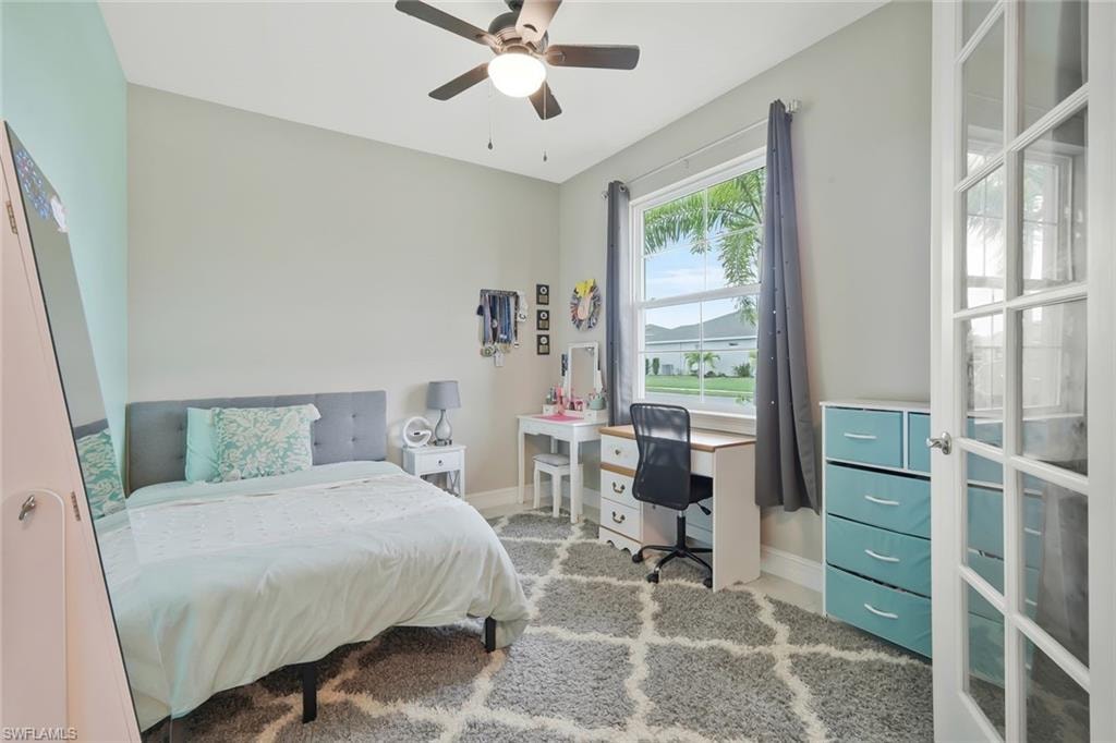 Bedroom featuring ceiling fan, light carpet, and a desk