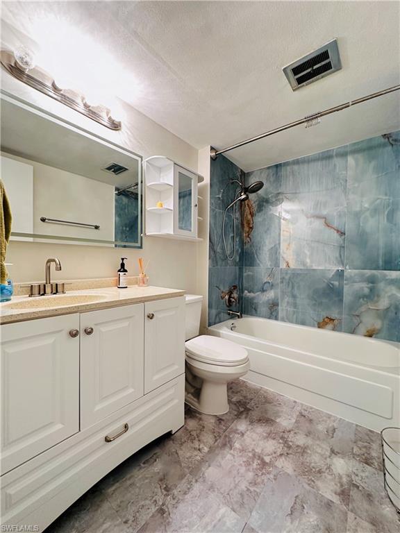 Bathroom featuring tub / shower combination, vanity, and a textured ceiling