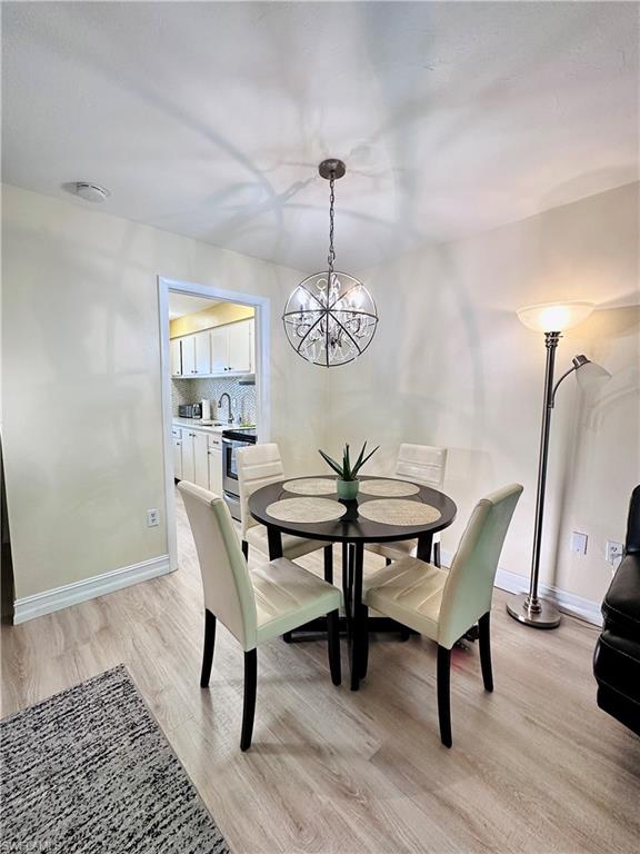 Dining room with light wood finished floors and a chandelier