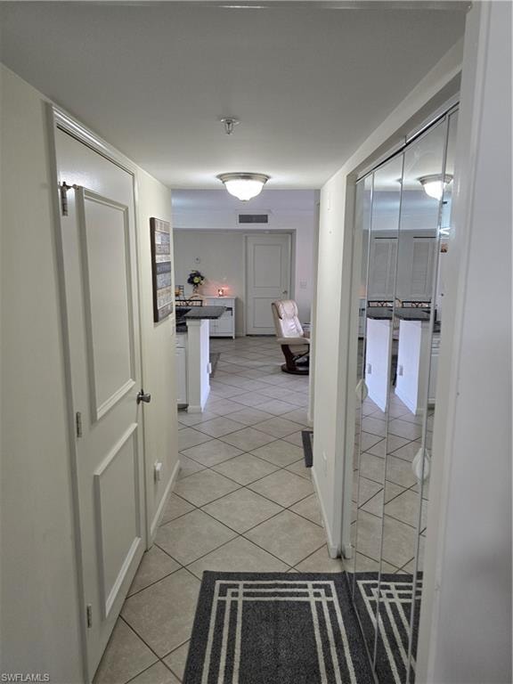 Hall featuring baseboards, visible vents, and light tile patterned floors
