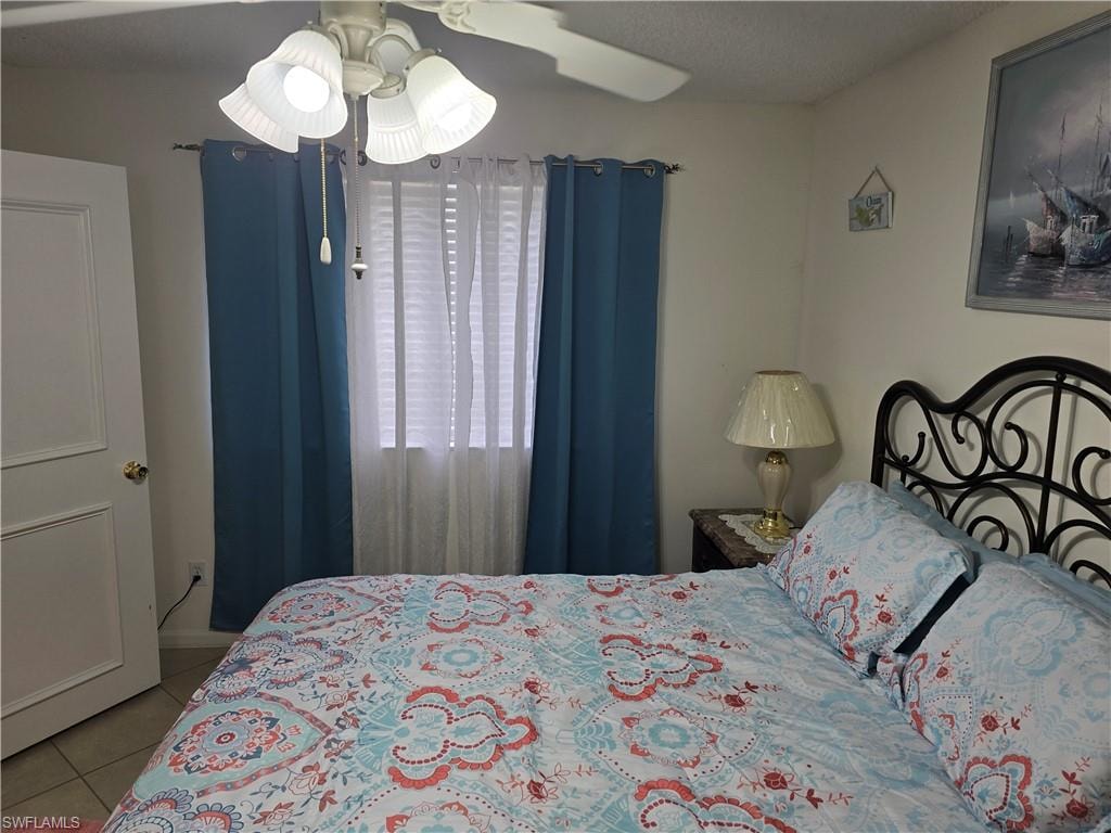 Tiled bedroom featuring a ceiling fan