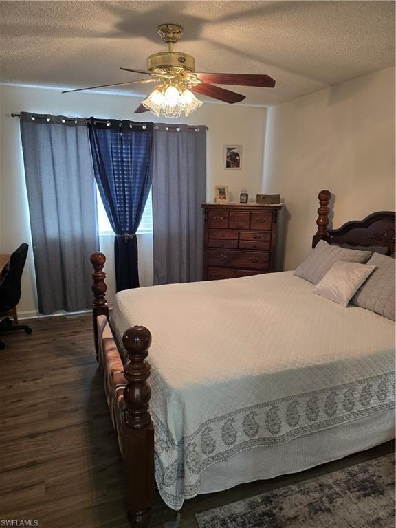 Bedroom with a textured ceiling, ceiling fan, dark wood finished floors, and a desk