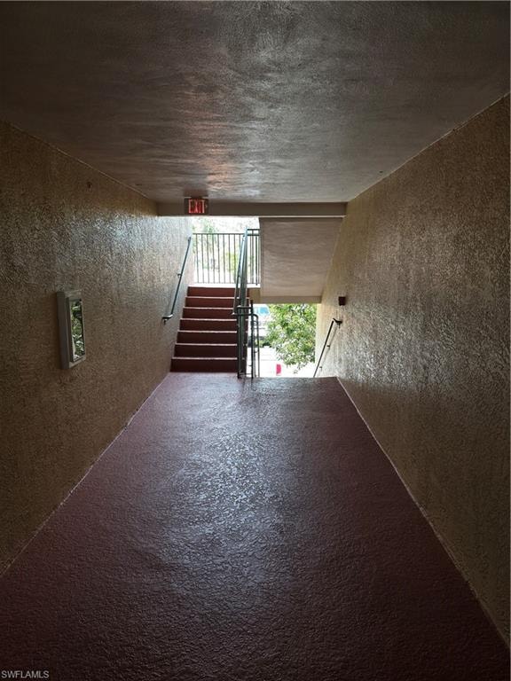 Empty room featuring a textured ceiling, a textured wall, and stairway