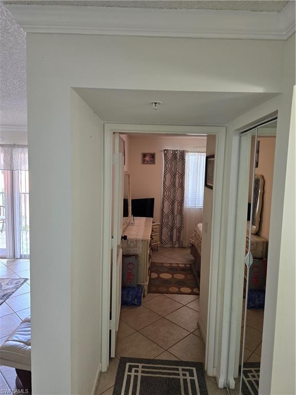 Corridor featuring crown molding and light tile patterned floors