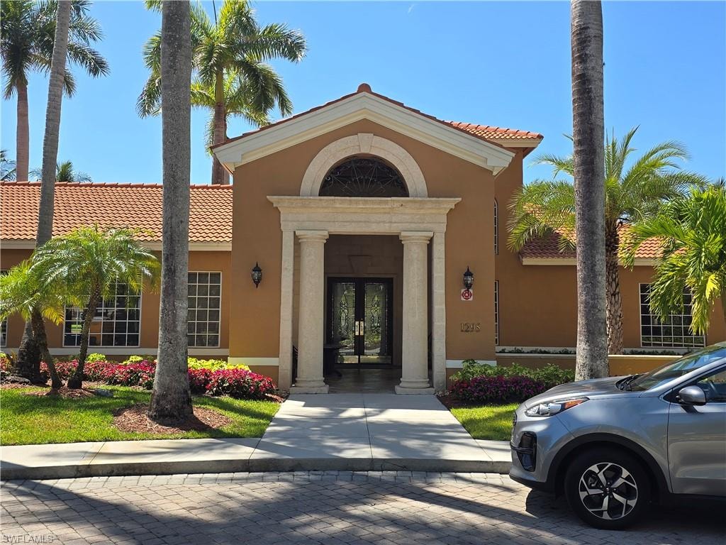 Doorway to property featuring french doors, stucco siding, and a tile roof