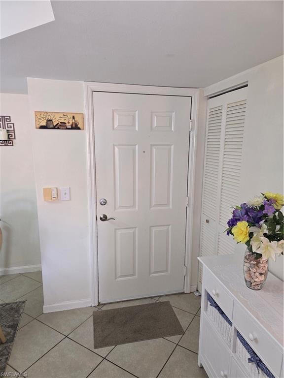 Doorway to outside with light tile patterned floors and baseboards