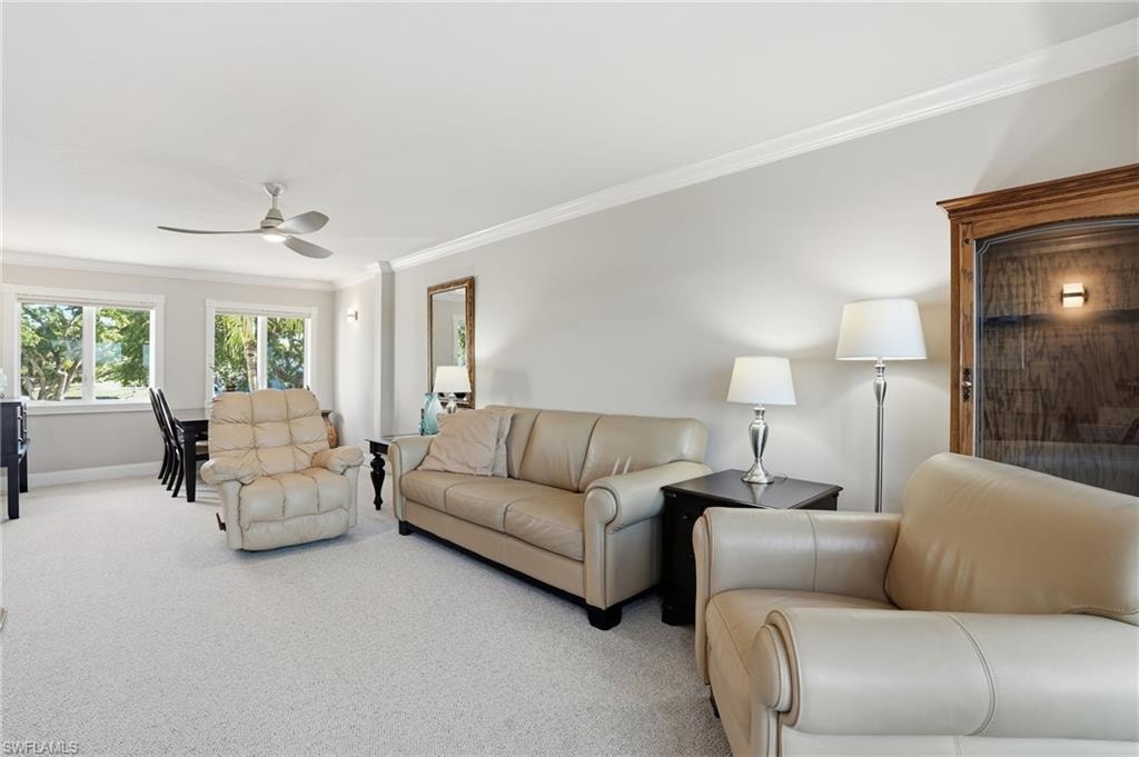 Carpeted living area with ornamental molding and a ceiling fan