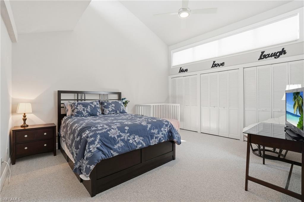 Carpeted bedroom featuring multiple closets, high vaulted ceiling, and a ceiling fan
