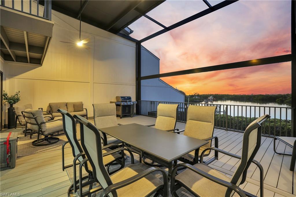 Wooden deck featuring outdoor dining area, glass enclosure, area for grilling, a sunroom, and a water view