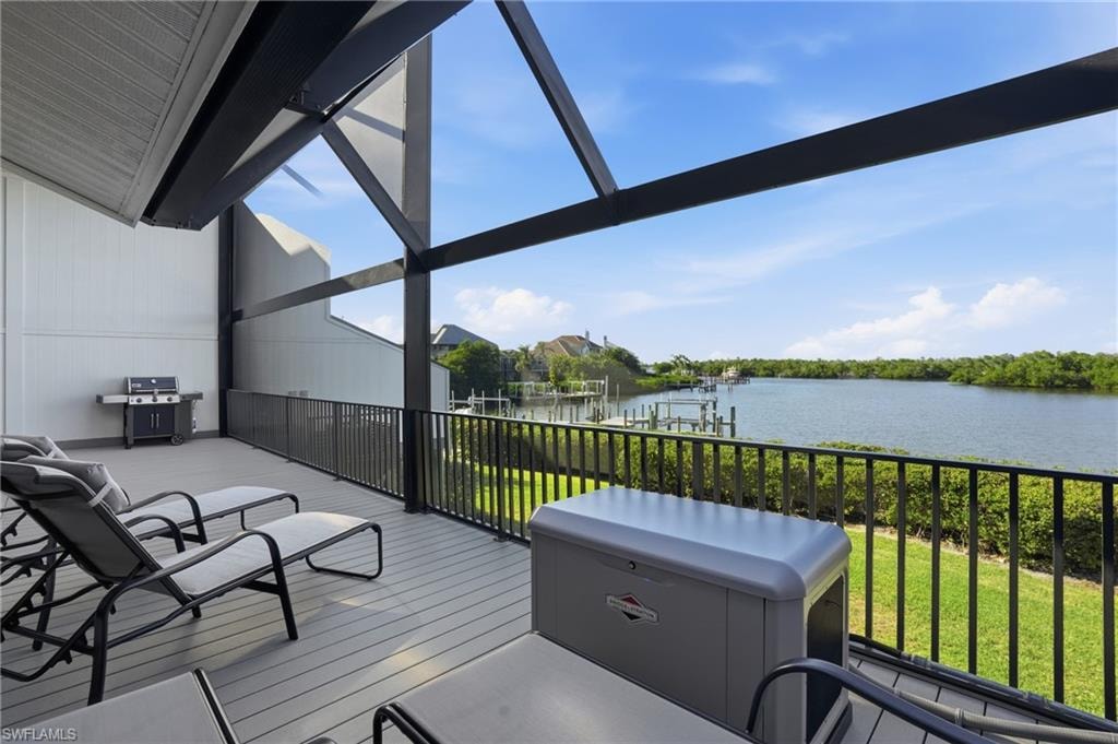 Wooden deck featuring area for grilling, a boat dock, a water view, and a lawn