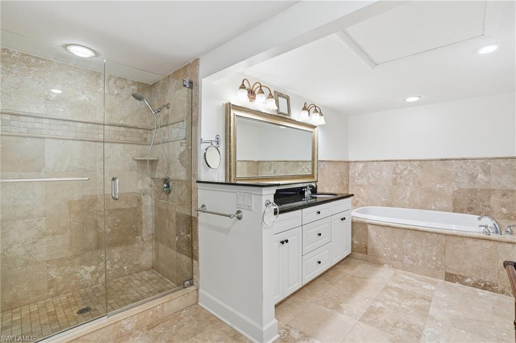 Bathroom with double vanity, a bath, and a shower stall