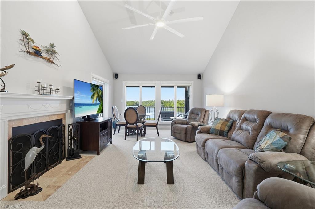 Living room with high vaulted ceiling, a tile fireplace, and a ceiling fan