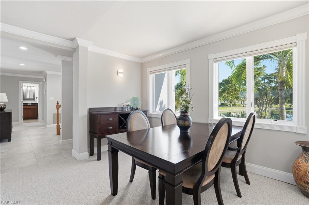 Dining space with light colored carpet and crown molding