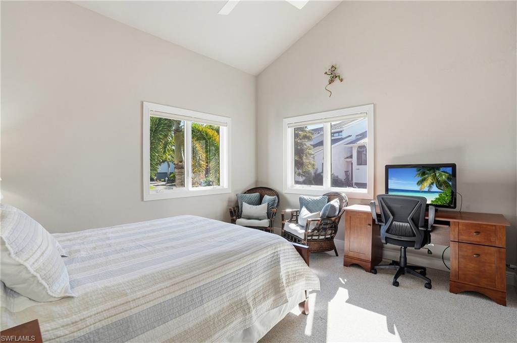 Bedroom with a desk, light colored carpet, a ceiling fan, and high vaulted ceiling