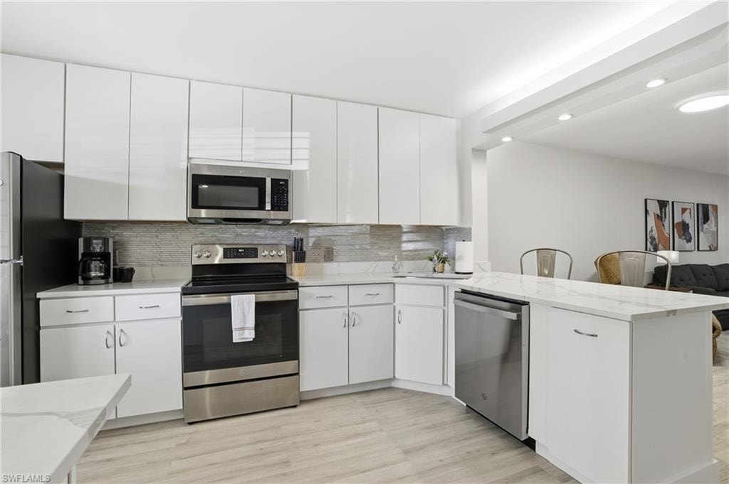 Kitchen featuring stainless steel appliances, light wood-style flooring, white cabinets, and recessed lighting