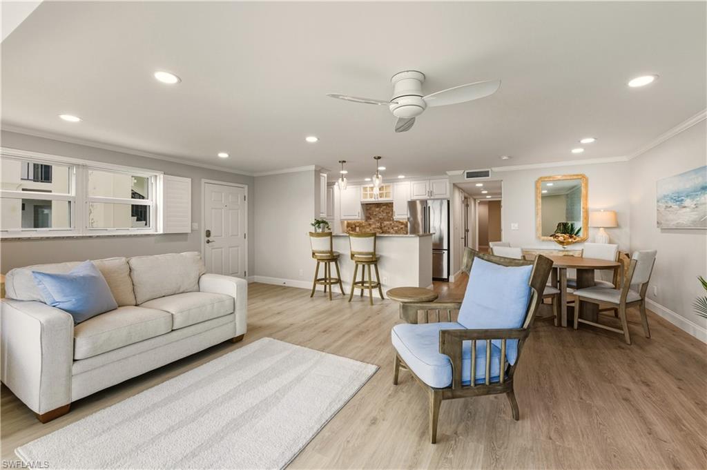 Living area featuring light vinylflooring, a ceiling fan, crown molding, and recessed lighting