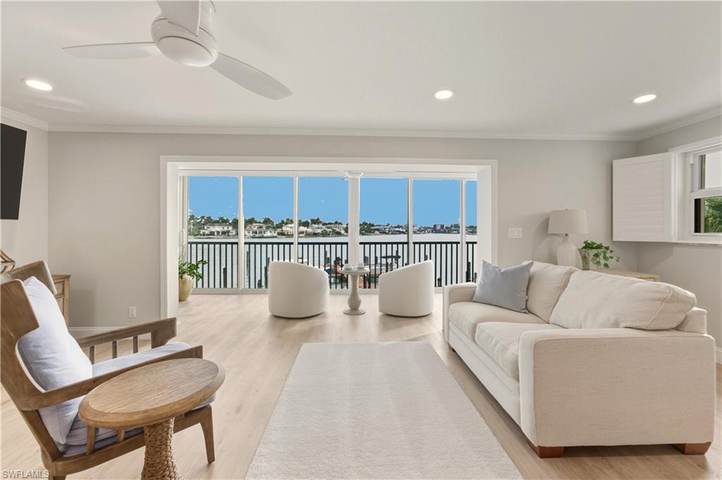Living area featuring healthy amount of natural light, light vinyl floors, recessed lighting, ornamental molding, and a water view