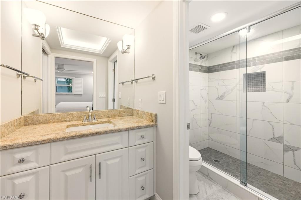 Ensuite bathroom featuring a stall shower, vanity, and light tile finish floors