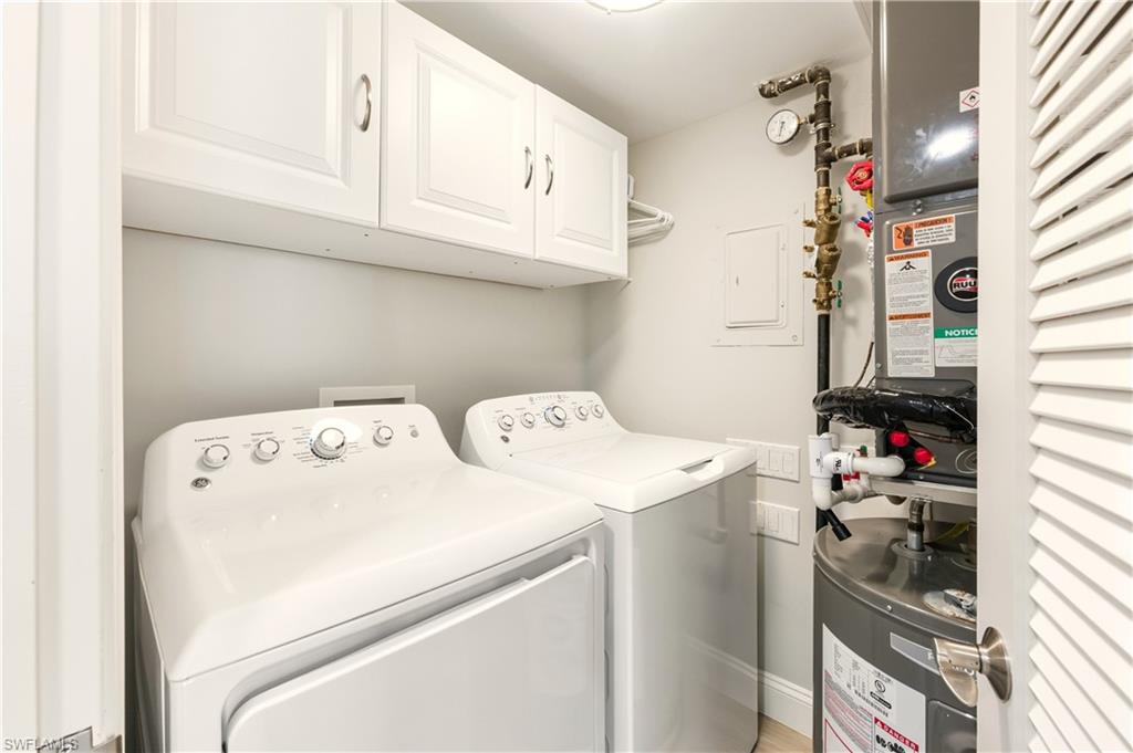 Laundry room with cabinet space, water heater, electric panel, and washer and clothes dryer