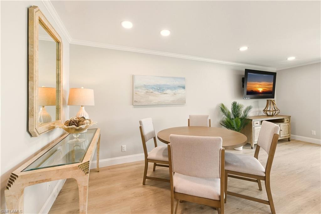 Dining room with light vinyl flooring, ornamental molding, and recessed lighting