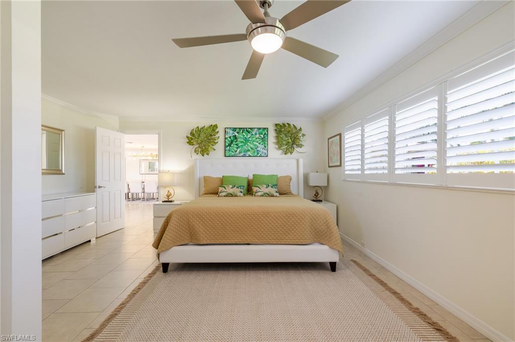 Bedroom with ornamental molding, light tile patterned floors, multiple windows, and a ceiling fan
