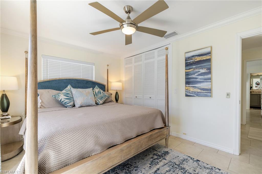 Tiled bedroom with crown molding, a ceiling fan, and a closet
