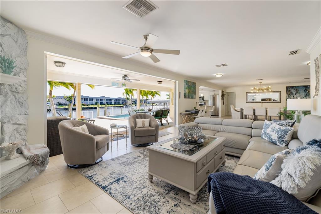 Living area with crown molding, light tile patterned floors, and ceiling fan