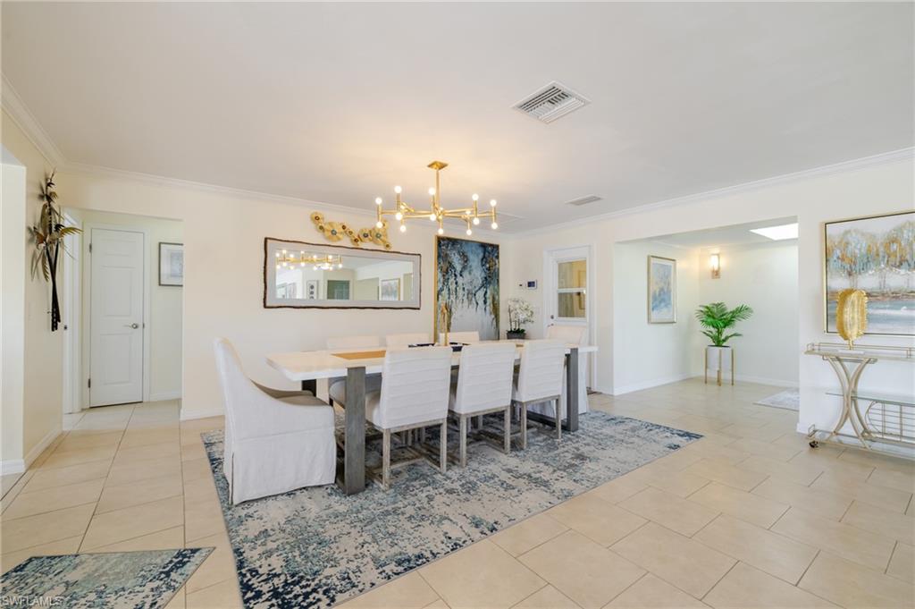 Dining area featuring crown molding, light tile patterned flooring, and a chandelier