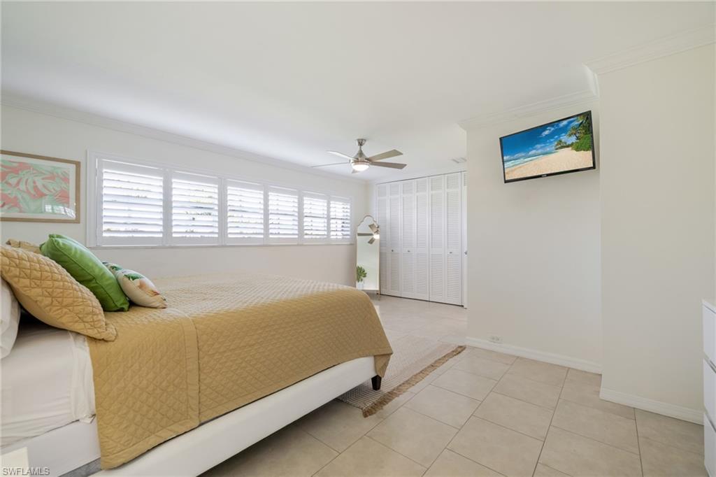 Bedroom with ornamental molding, a closet, ceiling fan, and light tile patterned floors