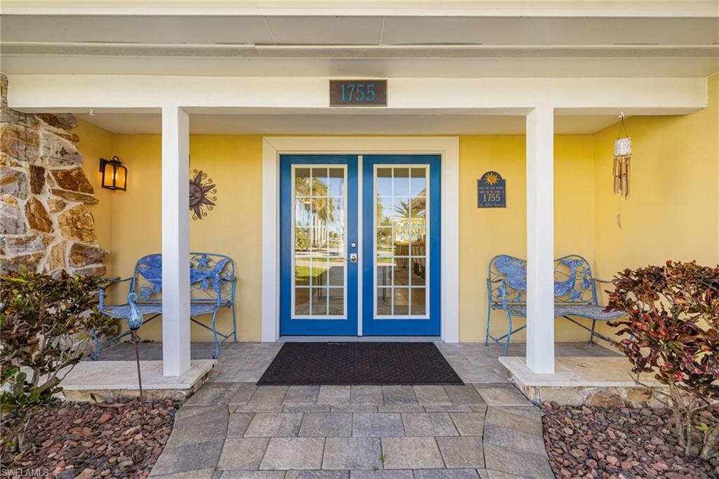 View of exterior entry with french doors, stucco siding, and a porch
