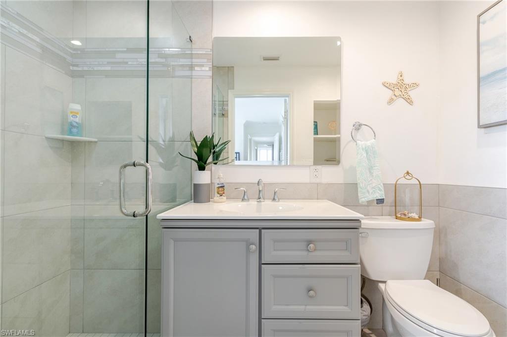 Full bathroom with vanity, a shower stall, and tile walls