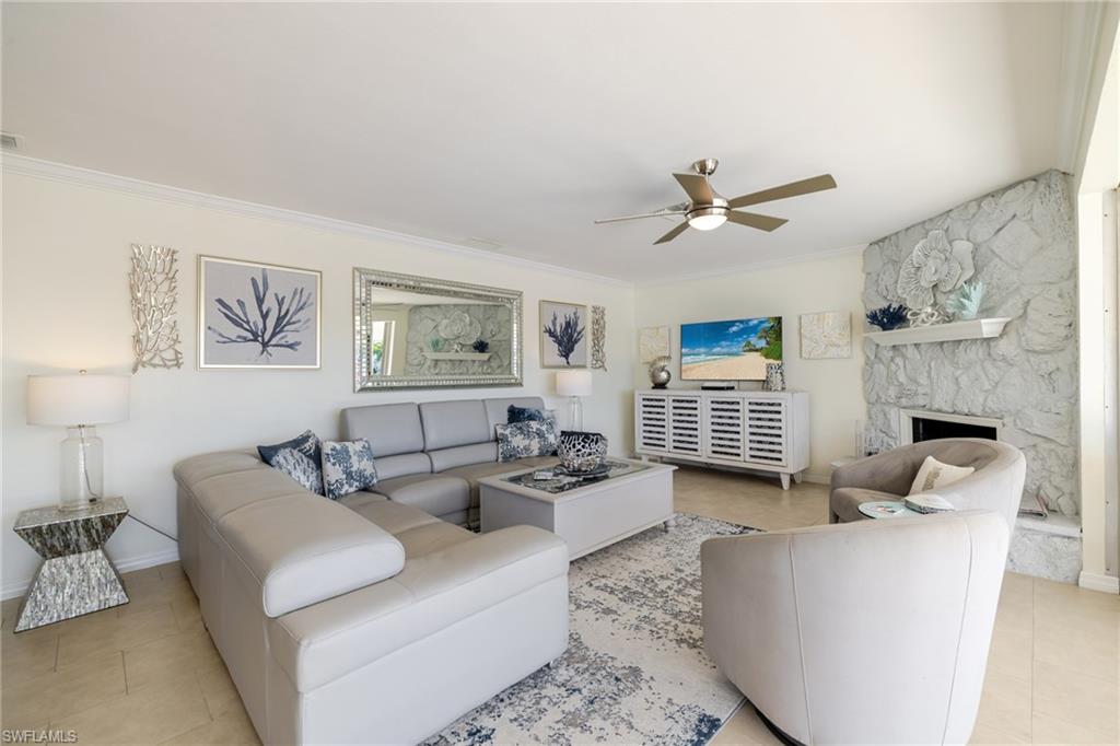 Tiled living area featuring a fireplace, ornamental molding, and a ceiling fan