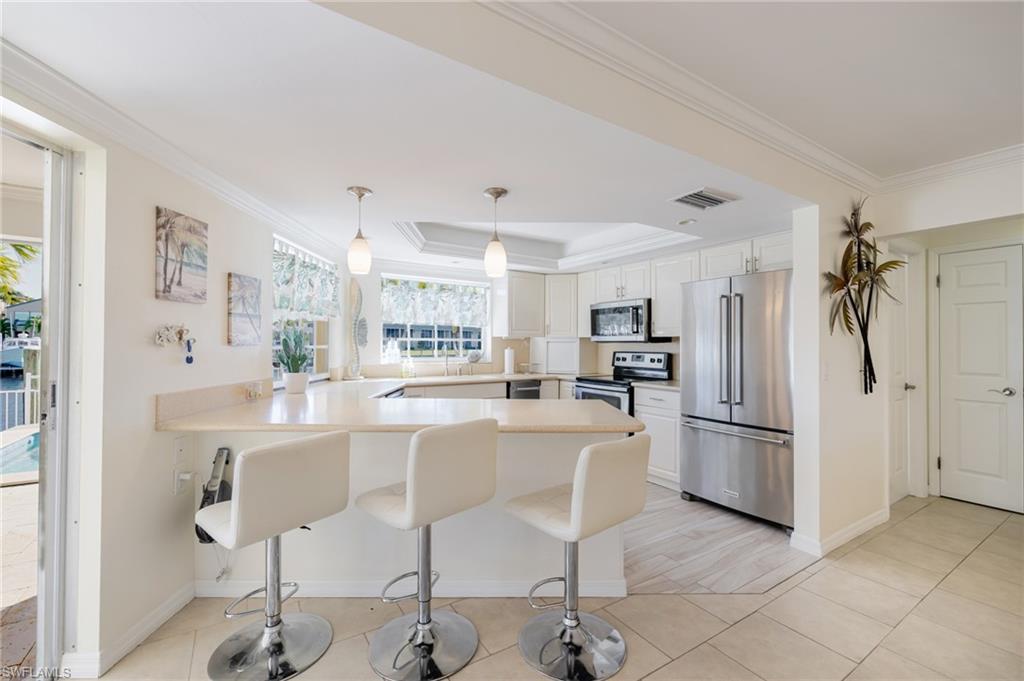 Kitchen with stainless steel appliances, crown molding, a raised ceiling, a peninsula, and a breakfast bar