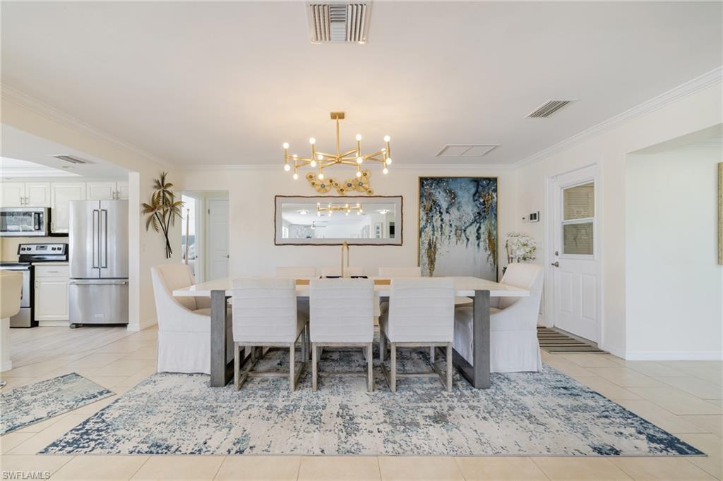 Dining room featuring ornamental molding, a chandelier, and light tile patterned floors