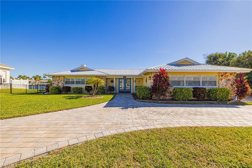 Single story home featuring french doors, stone siding, a porch, and a metal roof